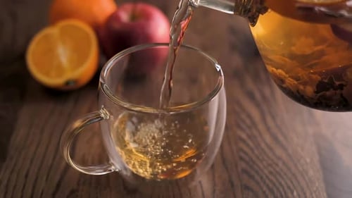 Pouring Refreshing Fruit Tea into Glass Mug