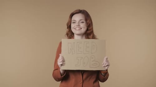 Medium Isolated Video of a Joyful and Active Young Woman Holding a Piece of Cardboard That Says