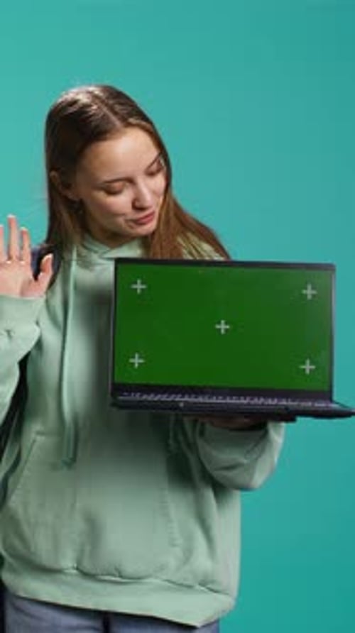 Vertical Video Smiling Woman Presenting Laptop with Green Screen Display