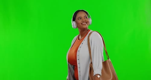 Green screen, smile and black woman walking, headphones and streaming music against studio