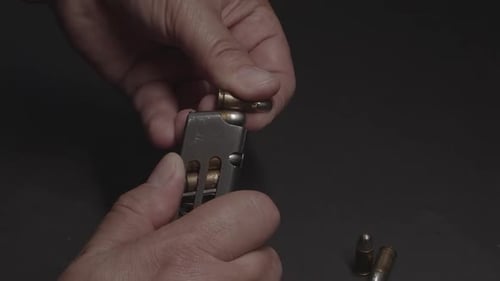 Hands Loading Bullets into a Firearm Magazine