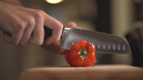 Chef's Hand Slicing A Red Sweet Bell Pepper To Remove The Seeds. - close up shot