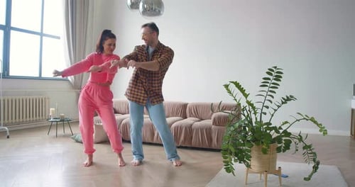 Enthusiastic Couple Dances Together Barefoot in Living Room