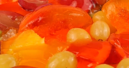 Falling grapes on a multi-colored berry gelatin jelly with orange and kiwi slices