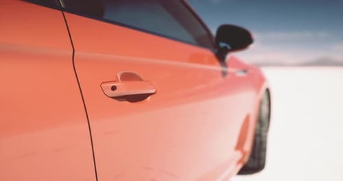 Modern Orange Car Driving on a Vast Salt Flat Landscape