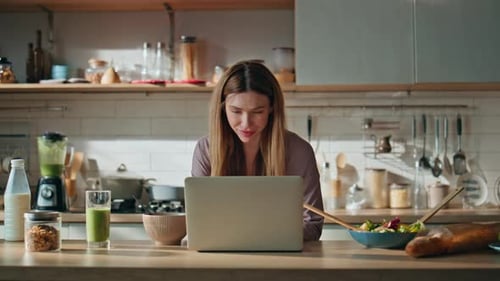 Woman Works on Laptop in Bright Kitchen