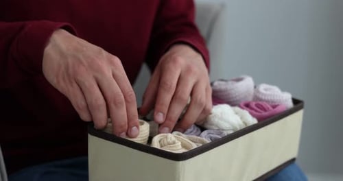 Homme mettant des chaussettes dans un organiseur à la maison, gros plan
