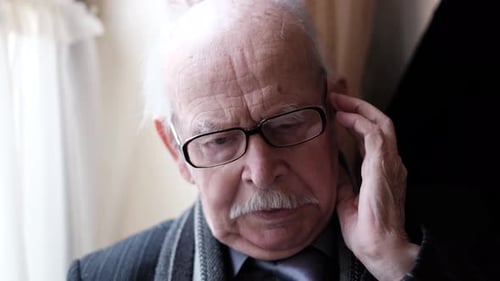 An Elderly Man Sits in a Chair with a Headache His Worry Wrinkles His Forehead Stress and Reasoning