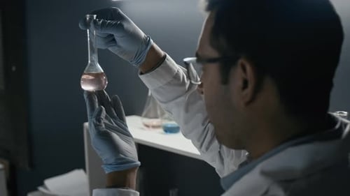 Scientist examining pink solution in laboratory setting