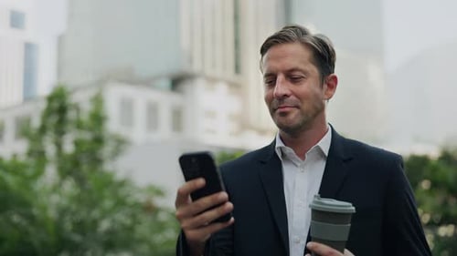 Businessman Using Phone Holding Coffee Outside Office Building