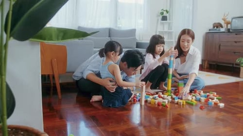 Asiatische Familie mit spielenden Kindern und Bauturm aus buntem Holzspielzeug