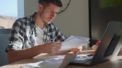 Worried Man Reviewing Household Bills at Home Desk