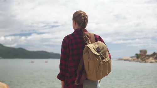 Female tourist with backpack is enjoying awesome sea view