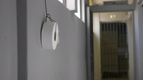 Toilet paper roll hanging from wire on a Mexican Hispanic prison wall hallway.