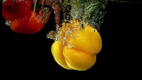 Mehrfarbige Paprika fallen unter Wasser, gefilmt mit einer Hochgeschwindigkeitskamera mit 1000 Bildern pro Sekunde