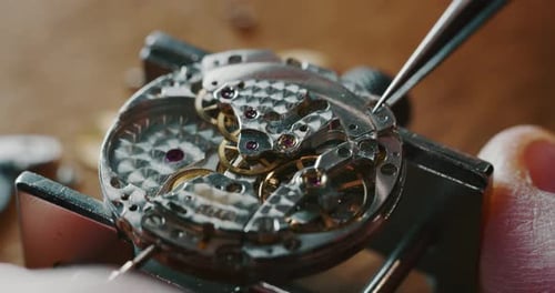 Slow motion close up of a professional watchmaker repairer working on a luxury mechanism watch gea