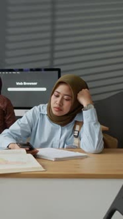 Asian Muslim Woman Student Looking at Smartphone in Classroom