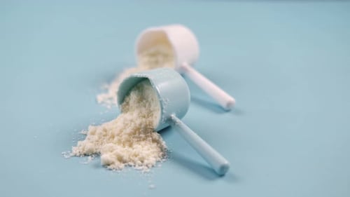 Close Up of Baby Milk Powder and Spoon on Tile Background