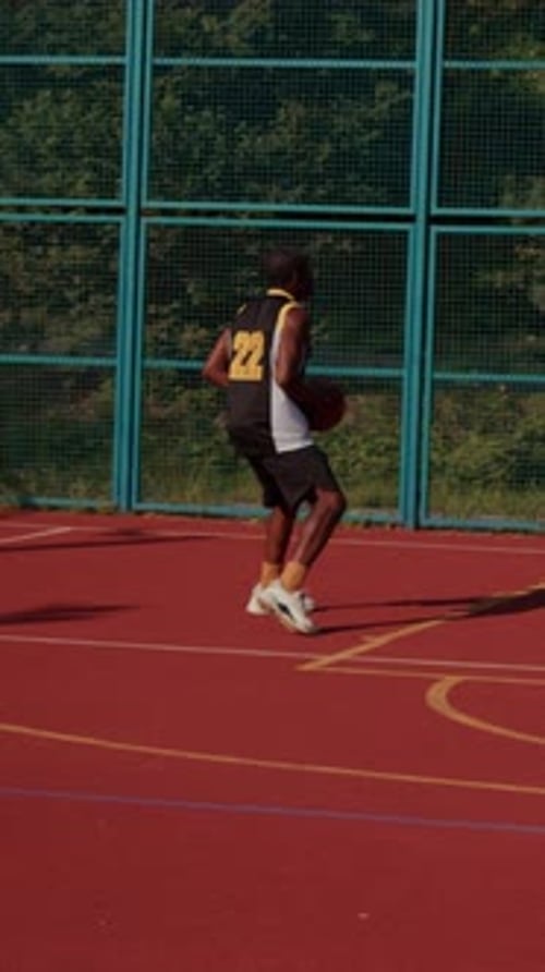 A Young Basketball Player Enthusiastically Dribbling the Ball Skillfully on the Court