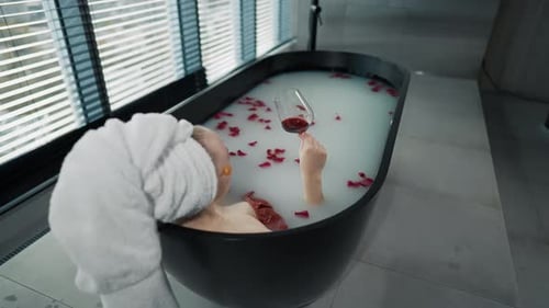Woman Relax in Milk Bath Drinking Wine Girl Added Eye Patches Resting Lying in Bath with Rose Petals