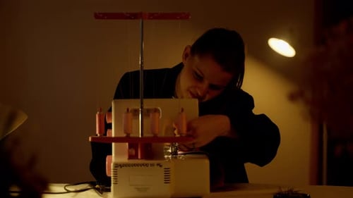 Woman Sewing Fabric with Sewing Machine at Night