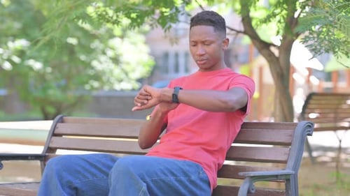 Young Adult Checks Smartwatch in City Park