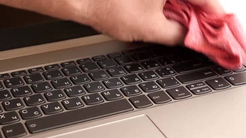 Hand Cleaning Laptop Keyboard with a Pink Cloth