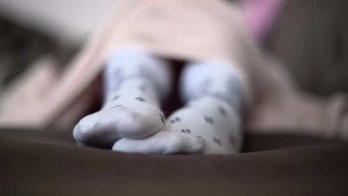 Woman moving feet in winter wool socks, close up, pink blanket