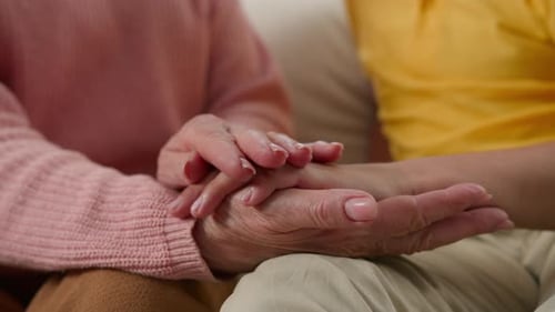 Adult Holding Hands of Senior in Loving Gesture