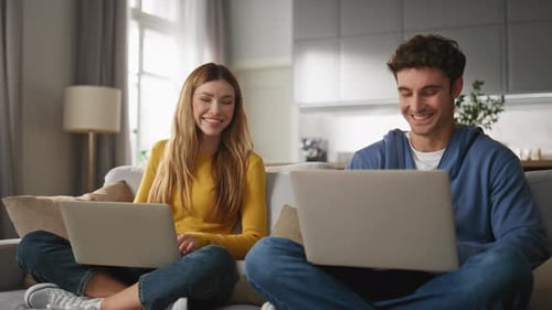 Couple Smiling and Working on Laptops at Home