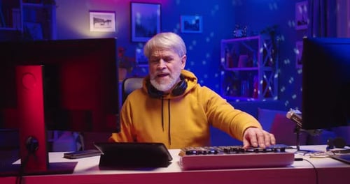 Portrait of Cheerful Caucasian Senior Man DJ Enjoying Hobby Playing Music at Home Recording Studio