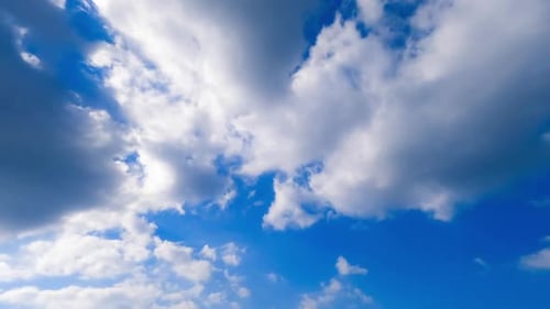 Transforming white clouds in the atmosphere. Azure summer sky with bright sun and clouds.
