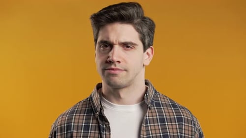 Man Displays Confused Expression Against Orange Background