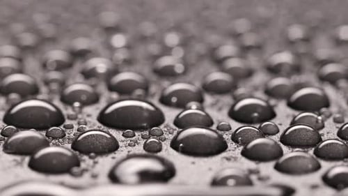 Gotas de água caindo sobre fundo cinza, closeup