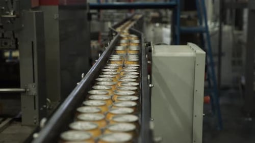 Close up of aluminium cans moving through converyor belt in packaging factory
