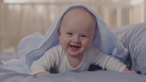 Adorable Baby Smiling Underneath a Light Blue Blanket