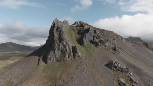 Dolly back view, icelandic mountain towering in distance, sunny day