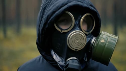 Child in pine forest with black gas mask on face