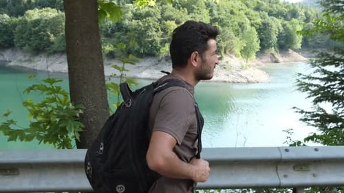 Man with Backpack Walking by Scenic Lake