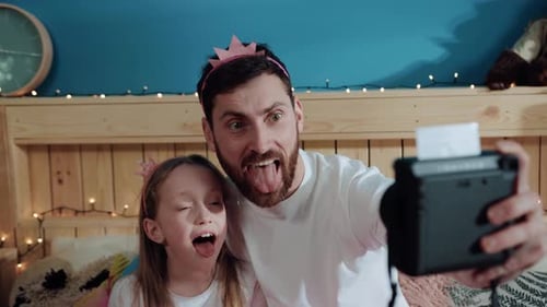 Silly Father and Daughter Take Instant Photo Together