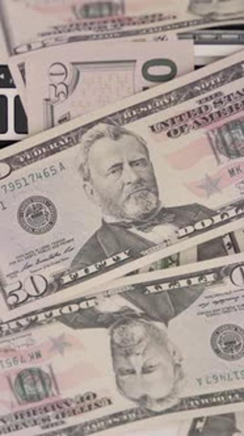 Pile of Fifty Dollar Bills on Laptop Keyboard