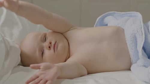 Infant Lying Down Yawns in Crib with Towel