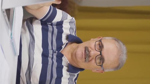 Vertical video of Home office worker old man says come to camera, calling you.