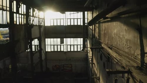 El sol brilla en el interior de una vieja fábrica industrial abandonada (toma aérea)