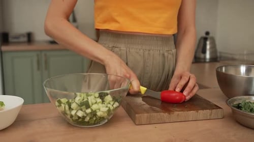 Woman Cuts Tomato for Salad in Sunny Kitchen