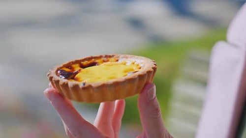 Das junge Ingwermädchen hält ein köstliches Pastel de Nata in der Hand und genießt die cremige Puddingfüllung und das flockige Cré