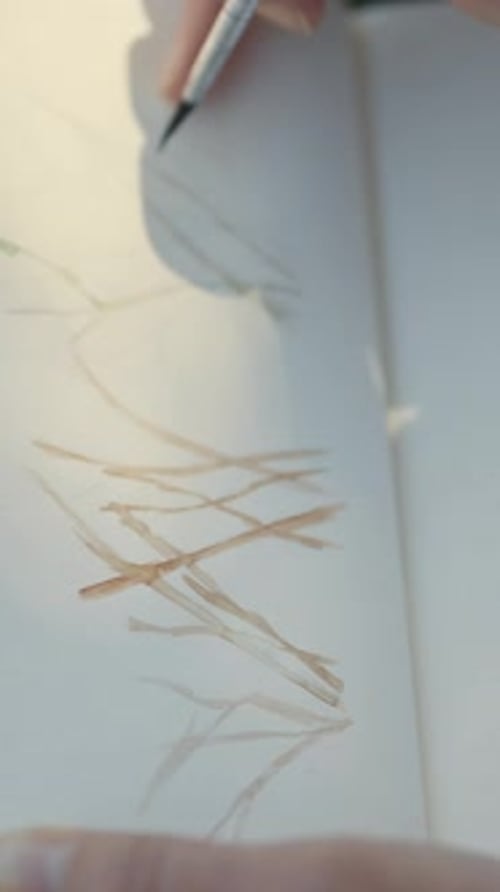 Nahaufnahme eines Blattes, auf dem der Künstler eine Aquarelllandschaft malt