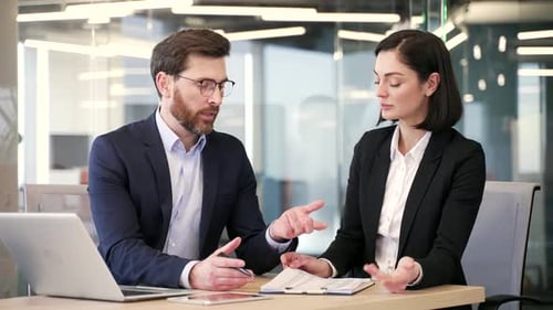 Business professionals collaborate while sitting at workplace in business office. Man and woman