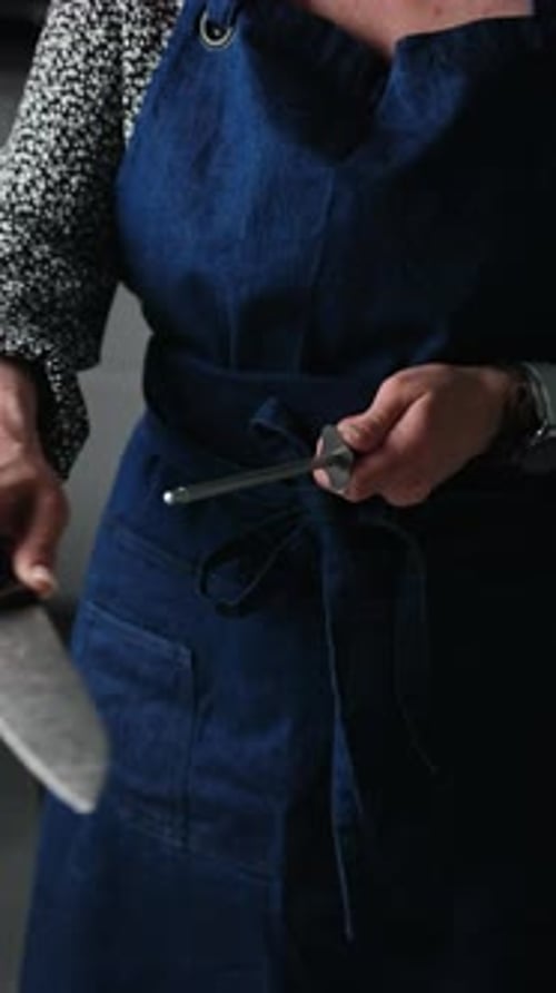 Girl In Apron Sharpening A Big Knife With Honing Rod Tool