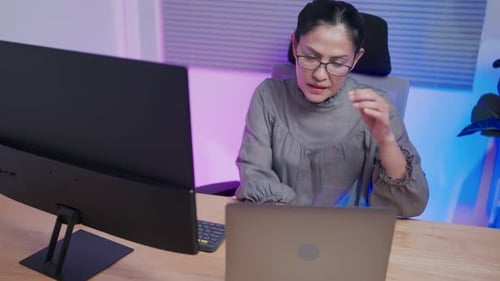 Woman Working at Night with Computer and Laptop